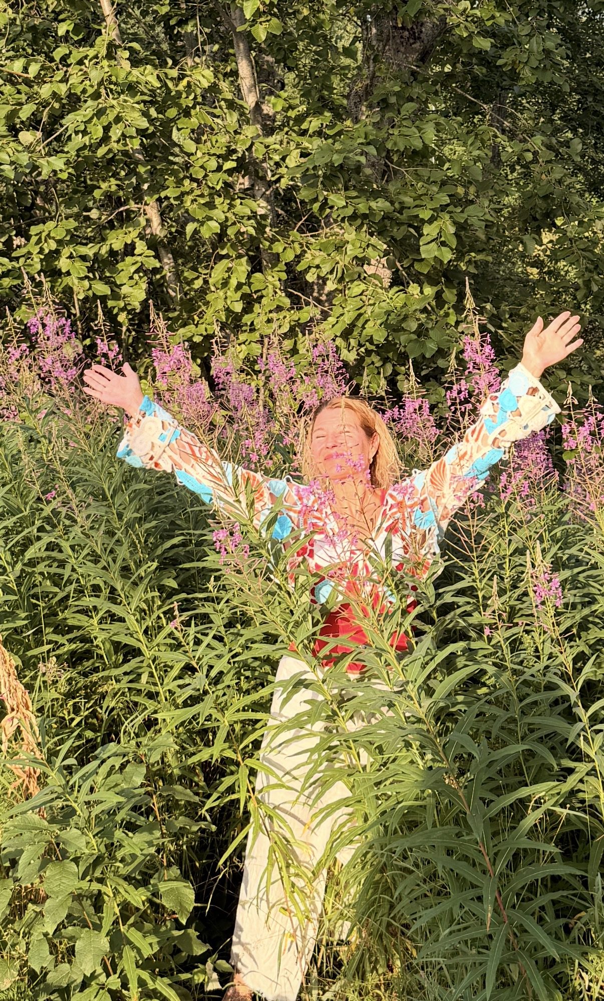 Edel Sirby med armene ut i en blomstereng